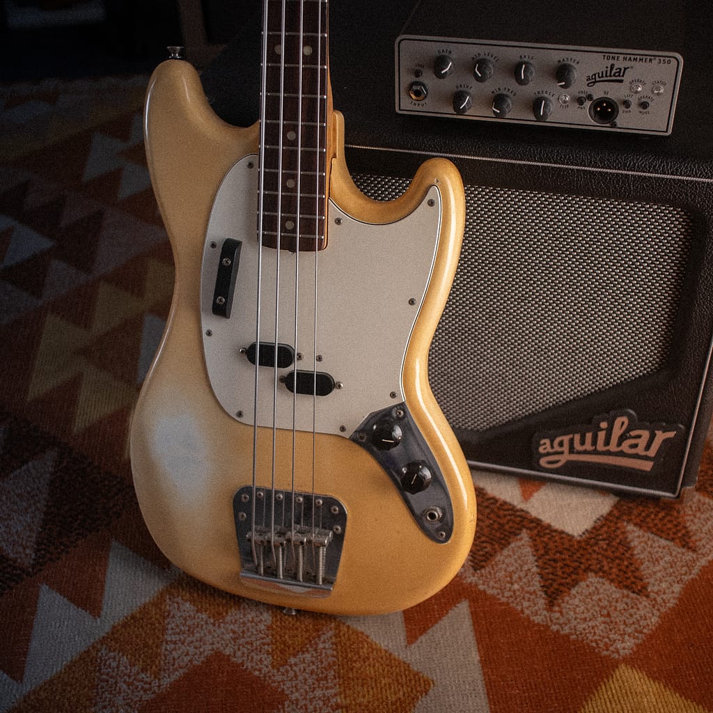 ein vintage fender bass auf einem teppich vor einem aguilar bass amp und passener box